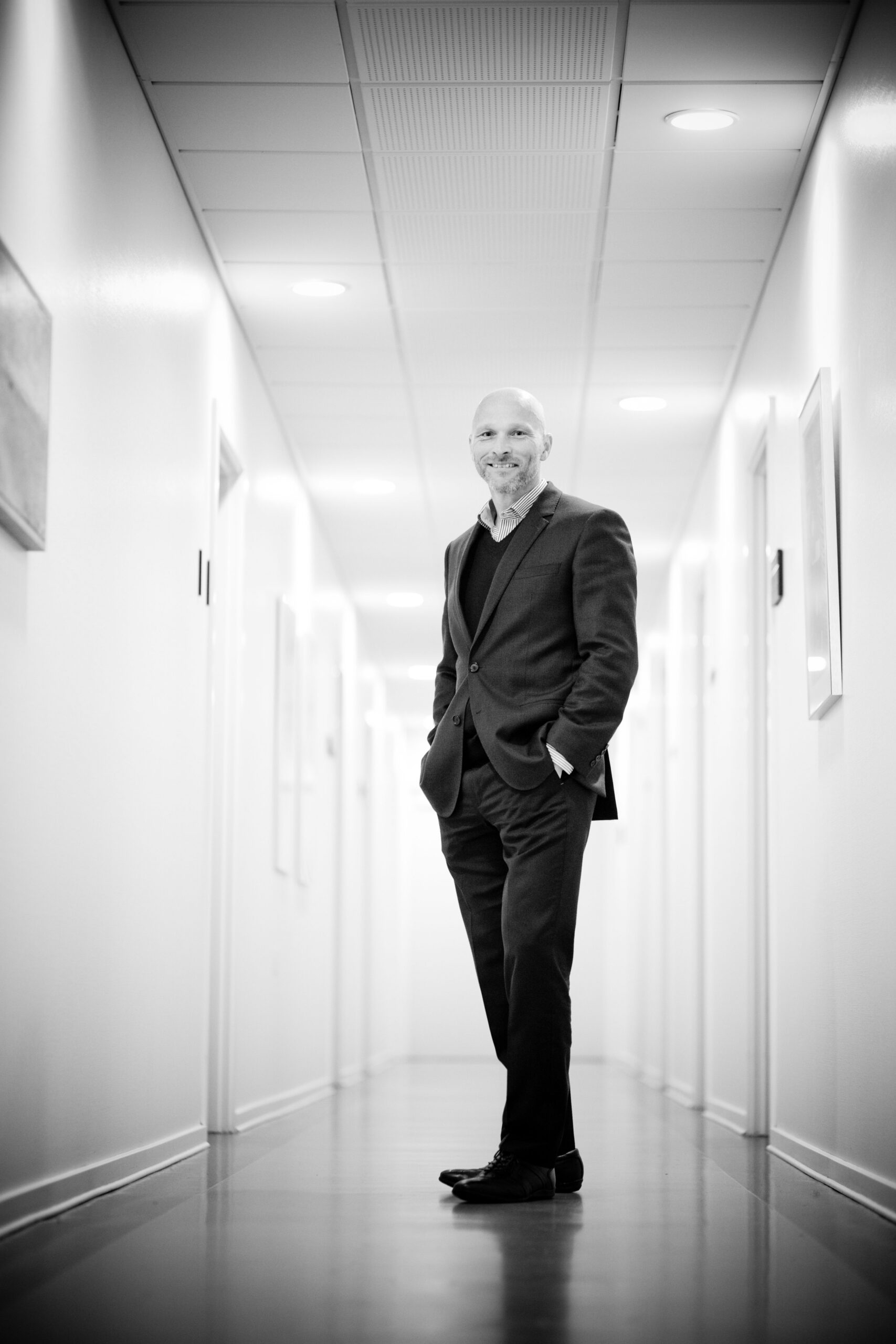 Professional businessman standing confidently in a modern office corridor.