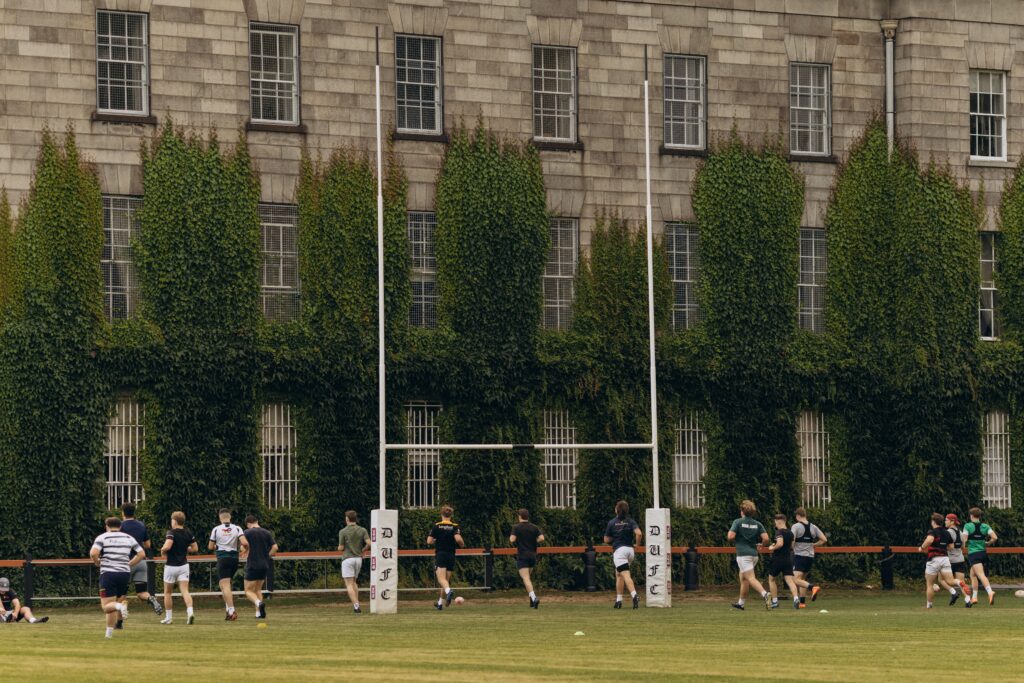 Rugby players practice on lush grounds of Trinity College Dublin.