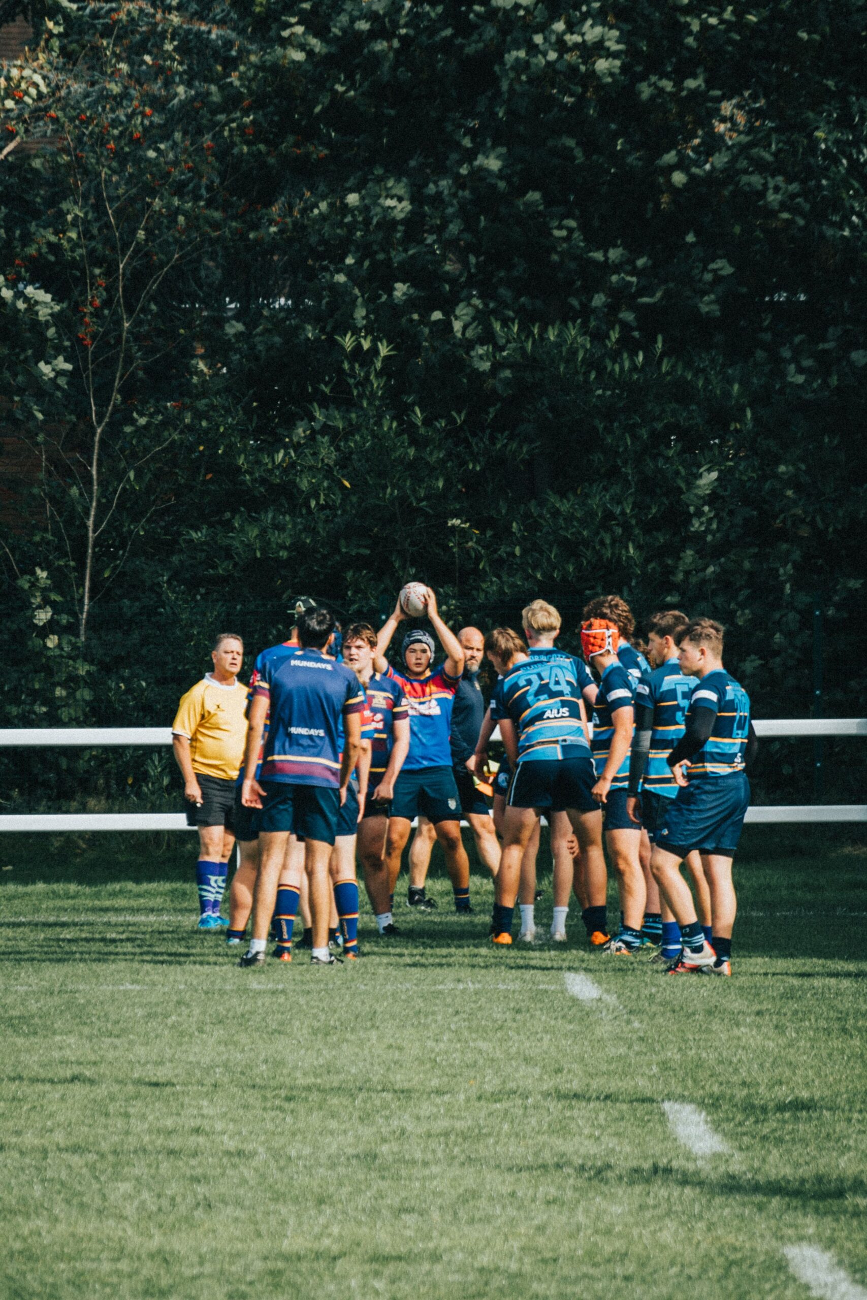 Rugby players in action during a daytime match on a grassy field.